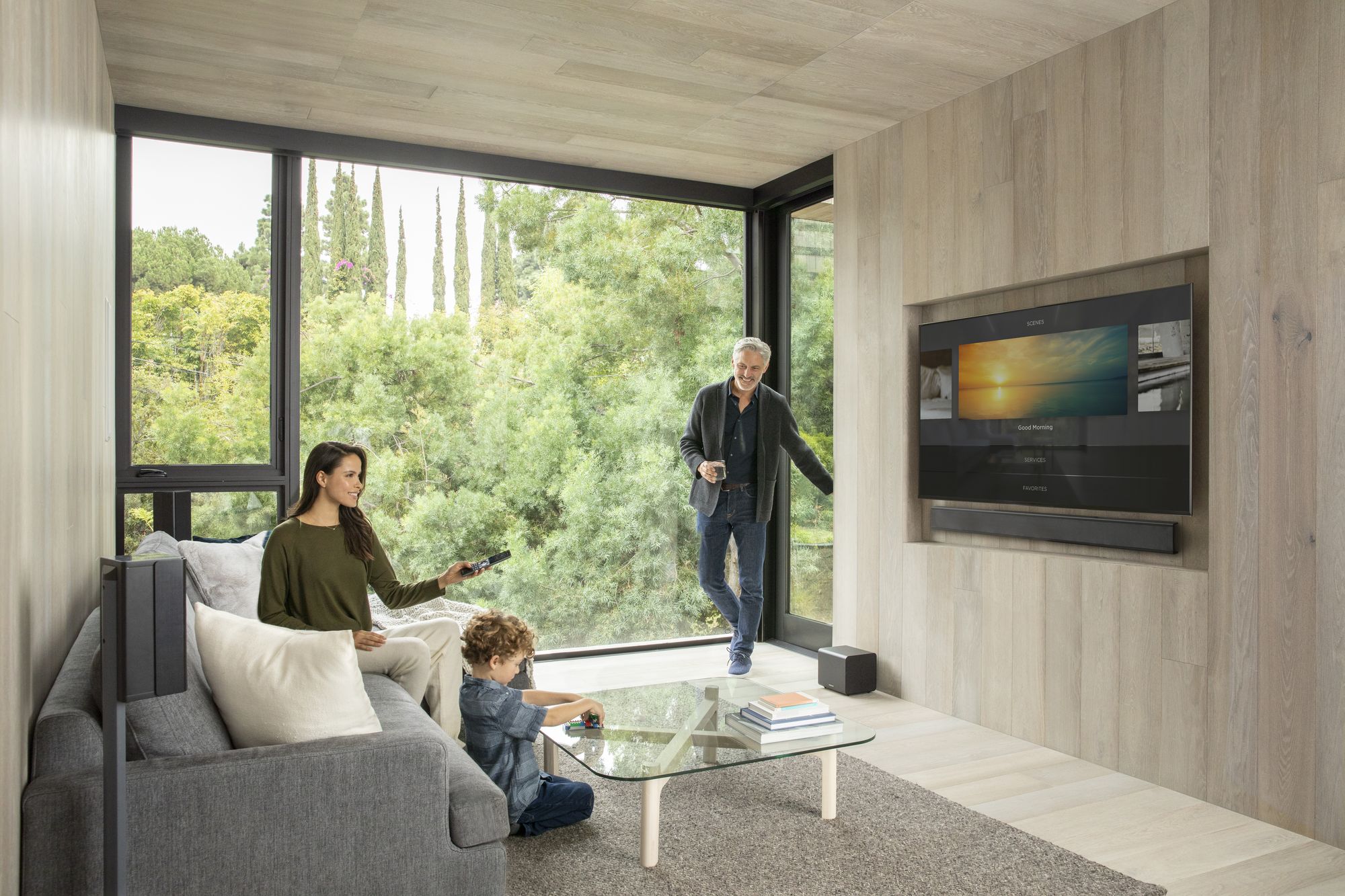 A family in a living room with a wall-mounted television and surround sound