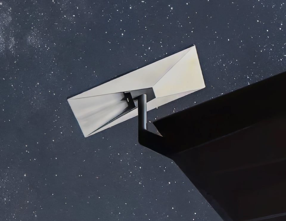 A Starlink dish on a slim pole mount at the eaves of a dark roof, against a starry night sky